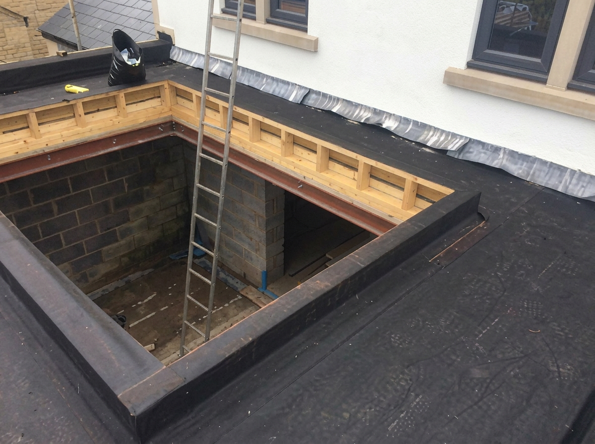 Watertight roof junction detail formed around a lightwell opening on a completed flat roof