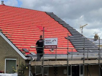 Full re-roof under way in Yorkshire with new breathable underlay and battens, tiles being laid on a scaffolded pitched roof